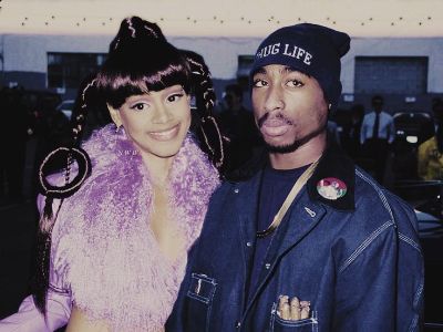 Lisa Lopes is wearing a pink glittery dress and Tupac is wearing a denim jacket.